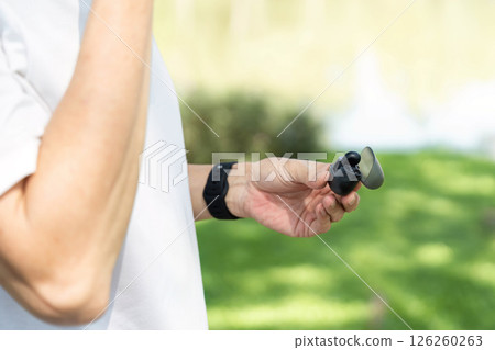 Wellness and Mindfulness. Close-up of a senior man's hand holding headphones, symbolizing relaxation. Wellness and Mindfulness. Close-up of a senior man's hand holding headphones, symbolizing relaxation. 126260263