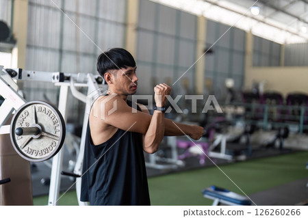 Stretching Exercises for Fitness at Gym A young man performs arm stretches Stretching Exercises for Fitness at Gym A young man performs arm stretches 126260266