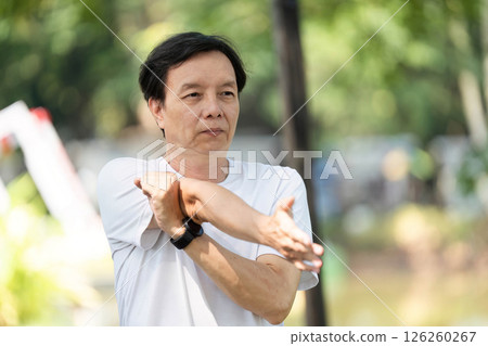 Wellness and Fitness. Senior man stretching his arms outdoors in a park for health. Wellness and Fitness. Senior man stretching his arms outdoors in a park for health. 126260267