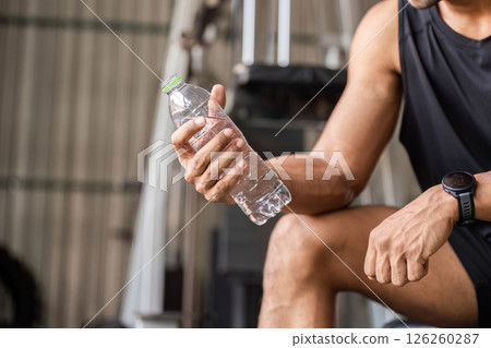 Fitness Hydration. Athlete holding a water bottle during a workout session in the gym. Fitness Hydration. Athlete holding a water bottle during a workout session in the gym. 126260287