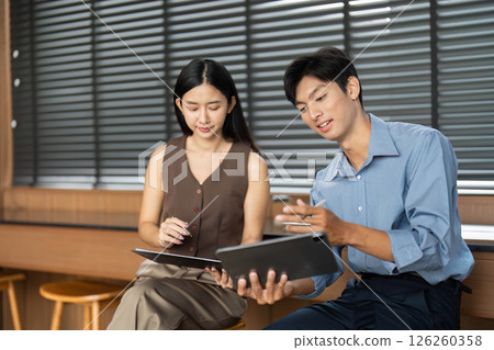 Business Collaboration and Discussion. Two professionals analyzing data on digital devices. 126260358