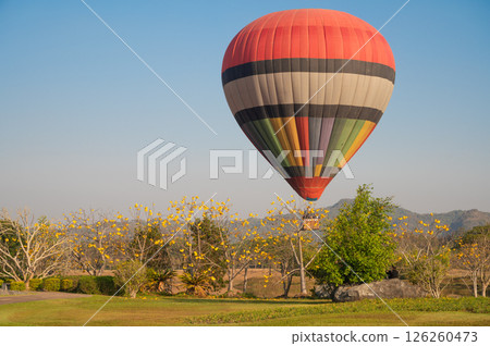 Hot air balloon prepare for landing on the field. Hot air balloons are aircraft that gain their lift by heating a large contained envelope of air above the ambient temperature. Hot air balloon prepare for landing on the field. Hot air balloons are aircraft that gain their lift by heating a large contained envelope of air above the ambient temperature. 126260473