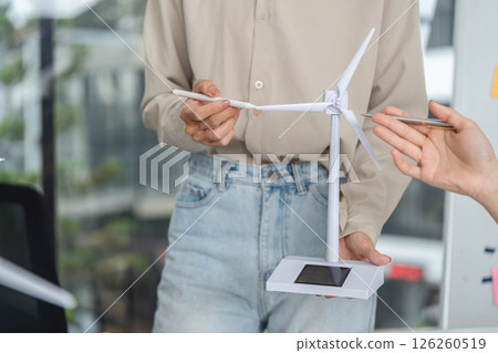 Innovative Energy Solutions. Professional presenting wind turbine model for sustainable business. Innovative Energy Solutions. Professional presenting wind turbine model for sustainable business. 126260519