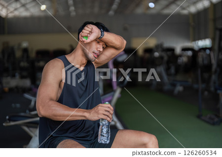 Hydration and Fitness: Man Taking a Break in Gym 126260534