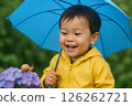 A boy smiles as he gazes at a snail on a hydrangea during the rainy season 126262721