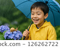 A boy smiles as he gazes at a snail on a hydrangea during the rainy season 126262722