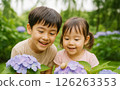 Smiling children gazing at hydrangeas and snails 126263353
