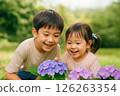 Smiling children gazing at hydrangeas and snails 126263354
