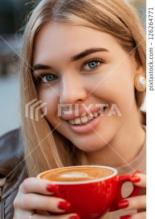 Woman Coffee Latte Smiling Outdoor - Closeup of a woman smiling while holding a red cup of latte outdoors. 126264771