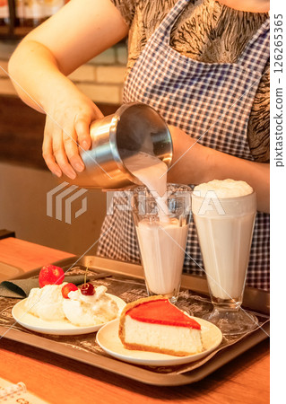 A waiter in a cafe prepares an order of milkshake, cheesecake and ice cream with fruit A waiter in a cafe prepares an order of milkshake, cheesecake and ice cream with fruit 126265365