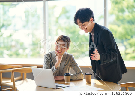 兩個人一邊看著筆記型電腦螢幕一邊交談 126265809