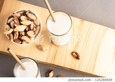 Brazil nut milk in glass with nuts on wooden board, showcasing healthy beverage options Brazil nut milk in glass with nuts on wooden board, showcasing healthy beverage options 126266609