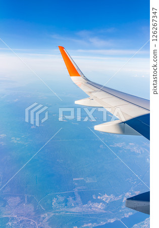 Aerial view from airplane window above green ground. View from the airplane window with beautiful clouds at sunrise 126267347