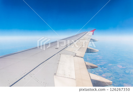 View from the airplane window at a beautiful cloudy sky and the airplane wing View from the airplane window at a beautiful cloudy sky and the airplane wing 126267350