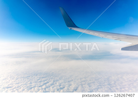 View from the airplane window at a beautiful cloudy sky and the airplane wing 126267407