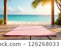 Pink yoga mat lying on wooden terrace, clear seascape blurred in background 126268033