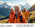 Company of happy elderly people in orange jackets on a walk along mountain trails 126268035
