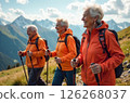 Elderly women in orange jackets hiking with trekking poles in the mountains 126268037