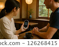 A man and a woman having a conversation in a cafe using a translator 126268415