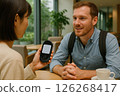 A man and a woman smiling and talking in a cafe through a translator 126268417