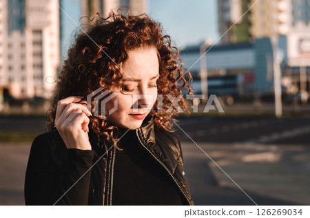 Beautiful girl with curly hair smiles against the backdrop of the city 126269034