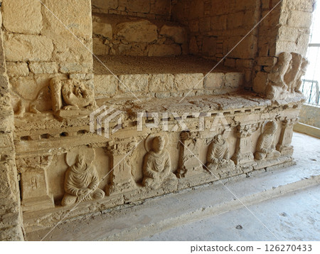 A Buddha statue on the base of the Buddha head at the ruins of the Molamoladu Buddhist monastery on the outskirts of Taxila, a strategic point east of Gandhara in Pakistan 126270433