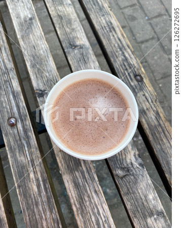 A paper cup of coffee stands on a bench in the street A paper cup of coffee stands on a bench in the street 126272695