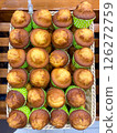 Freshly made cupcakes are laid out in a row on the counter in the store, vertical picture 126272759