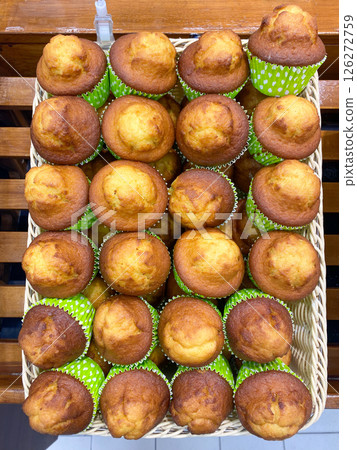 Freshly made cupcakes are laid out in a row on the counter in the store, vertical picture 126272759