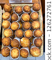 Freshly baked cupcakes are laid out in a row on the counter in the store, vertical picture 126272761
