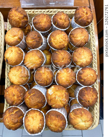 Freshly baked cupcakes are laid out in a row on the counter in the store, vertical picture 126272761