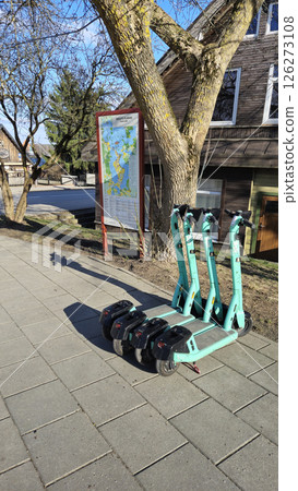 Trakai Lithuania - 03.28.2025 Row of parked electric scooters for rent on a paved sidewalk near a city map in the old town of Trakai on a sunny spring day 126273108