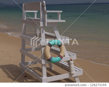 A Lifeguard Chair positioned on a Bright and Sunny Beach, along with a Lifebuoy nearby A Lifeguard Chair positioned on a Bright and Sunny Beach, along with a Lifebuoy nearby 126273144