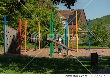 Children enjoy a sunny day on a colorful playground, climbing and exploring various equipment. The image captures a moment of outdoor fun with bright and vibrant surroundings. Children enjoy a sunny day on a colorful playground, climbing and exploring various equipment. The image captures a moment of outdoor fun with bright and vibrant surroundings. 126273148