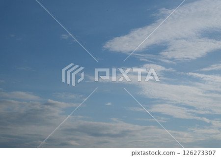 sky is blue and clear with no clouds. The sky is very bright and the sun is shining. on the right side there are white clouds 126273307