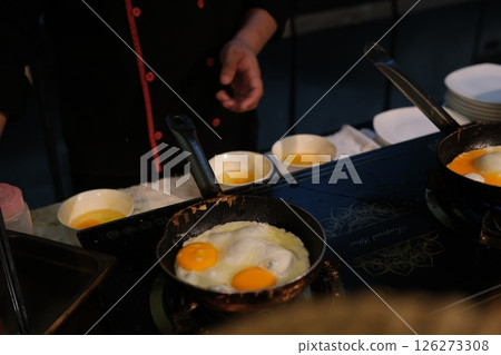Cooking eggs stove Delicious fried eggs with bacon and tomatoes in pan on stove, top view Cooking eggs stove Delicious fried eggs with bacon and tomatoes in pan on stove, top view 126273308