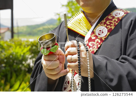 A monk ringing a chime at a cemetery 126273544