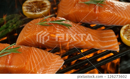 Close-up of Delicious Salmon Fillets on a Grill with Roaring Flames 126273602