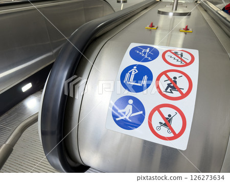 Modern escalator with detailed pictogram safety instructions on metallic surface. Focus on universal visual language for public space navigation and risk prevention Modern escalator with detailed pictogram safety instructions on metallic surface. Focus on universal visual language for public space navigation and risk prevention 126273634