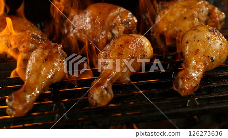 Close-up of Delicious Chicken Legs on a Grill with Roaring Flames 126273636