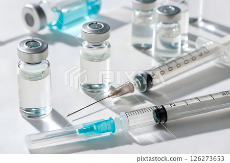 Medical vials with clear liquid and syringes arranged on white surface, healthcare and pharmaceutical concept, vaccination and treatment preparation, clinical research and medicine development 126273653