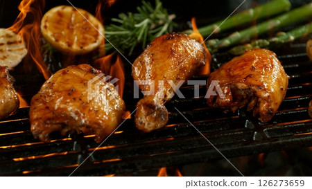 Close-up of Delicious Chicken Legs on a Grill with Roaring Flames 126273659