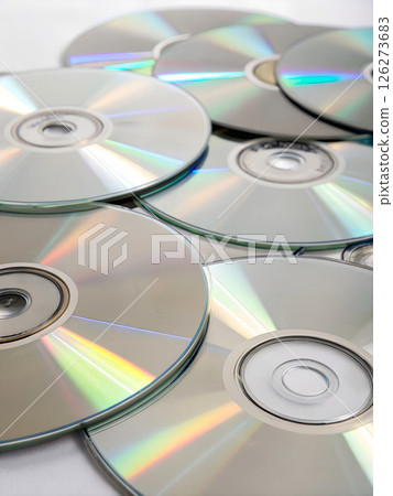 Stack of reflective compact discs with rainbow light reflections on white background, digital media storage and technology concept 126273683