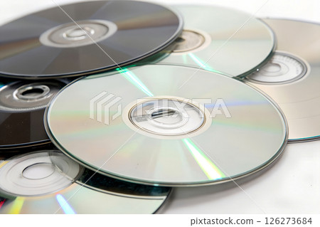 Stack of reflective compact discs with rainbow light reflections on white background, digital media storage and technology concept 126273684