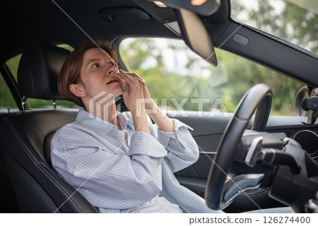 Woman drives car with broken air conditioning in hot summer weather wipes sweat paper napkin.  126274400