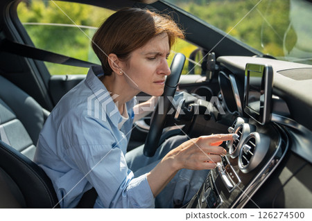 Bad smell from ac inside car. Woman driver feels an unpleasant odor after turn on air conditioning 126274500