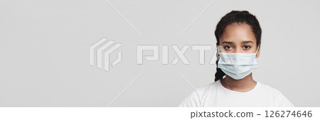 Flu concept. Teen african girl with protective face mask, grey studio background Flu concept. Teen african girl with protective face mask, grey studio background 126274646