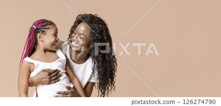 Mother and daughter connection. Happy afro woman cuddling little girl, looking to her child with love and care. 126274790