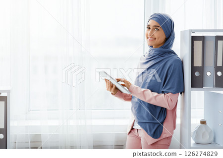 Modern Technologies For Office Work. Portrait Of Smiling Islamic Businesswoman Using Digital Tablet, Posing Near Window Indoors 126274829