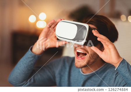 Excited Millennial Guy Using Virtual Reality Glasses Playing Videogame At Home In The Evening. Selective Focus 126274884